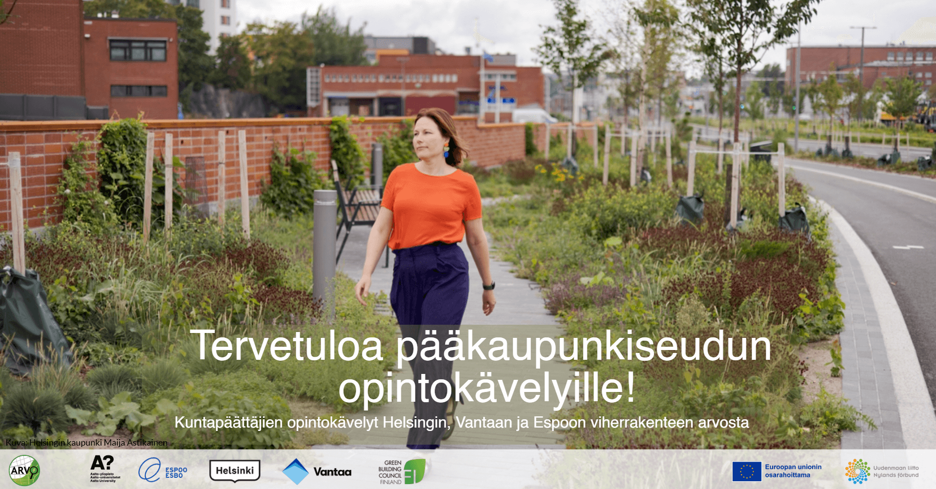 Nainen kävelee kadulla, viherkasveja